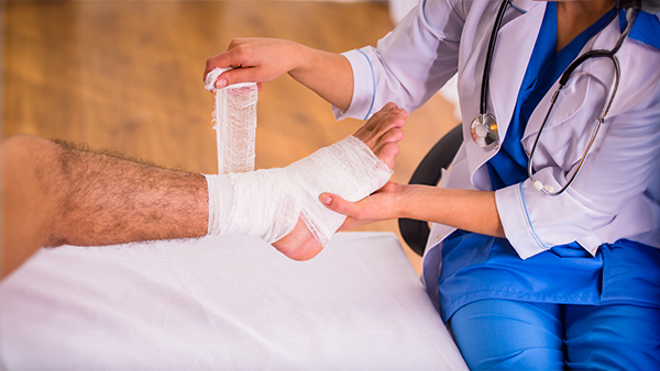 Healthcare professional applying a bandage to a patient's ankle.